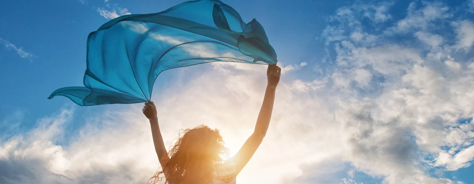 Beautiful young woman holding blue scarf on the wind .jpg